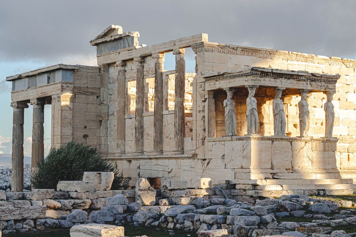 Ancient Erechtheion temple with caryatids at the Acropolis in Athens, Greece, illuminated by sunlight.